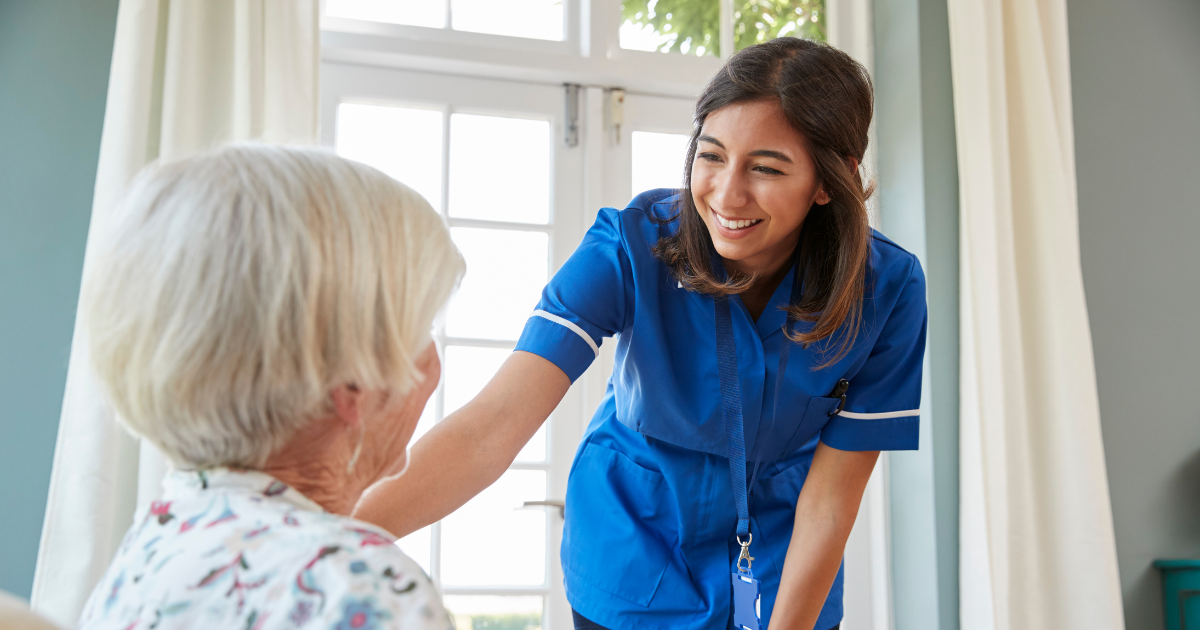 A woman enjoys her career in home health care as she helps a senior patient.