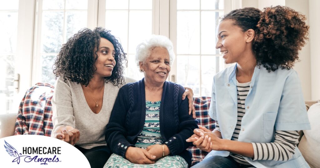 A caregiver talks with a client and her daughter, representing the type of communication that is vital when taking on a person-centered care approach.