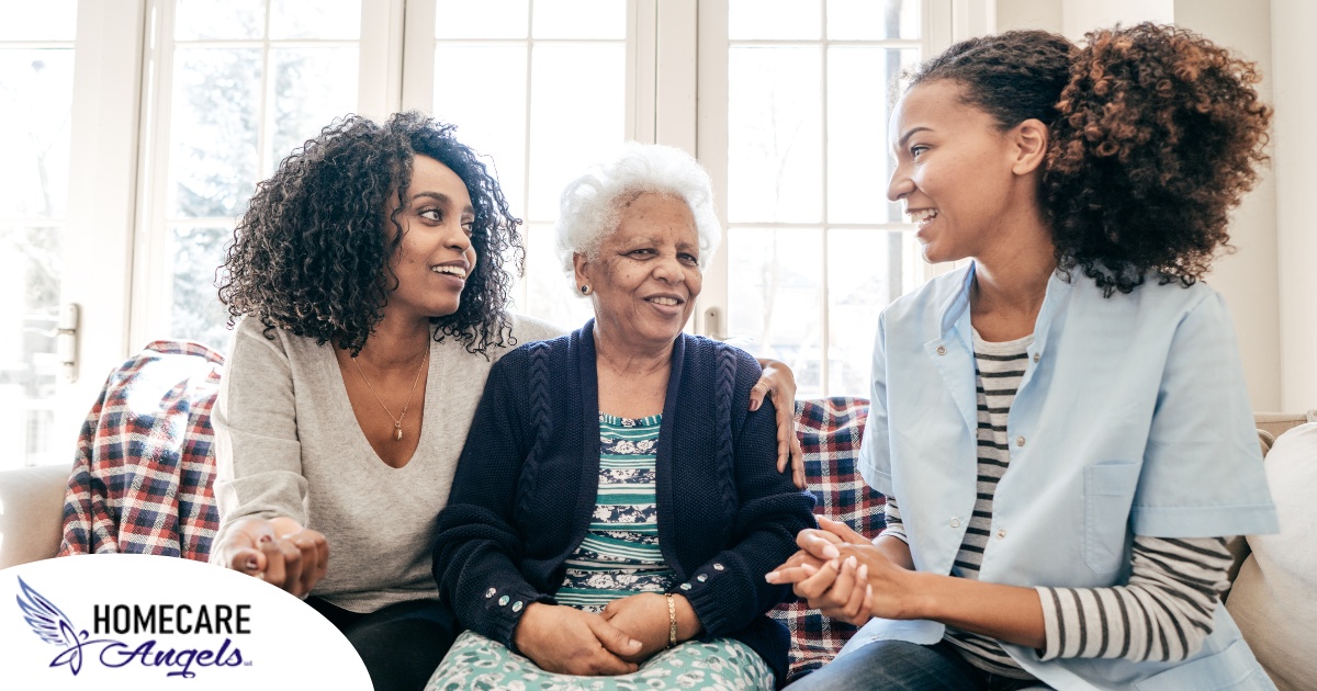 A caregiver talks with a client and her daughter, representing the type of communication that is vital when taking on a person-centered care approach.