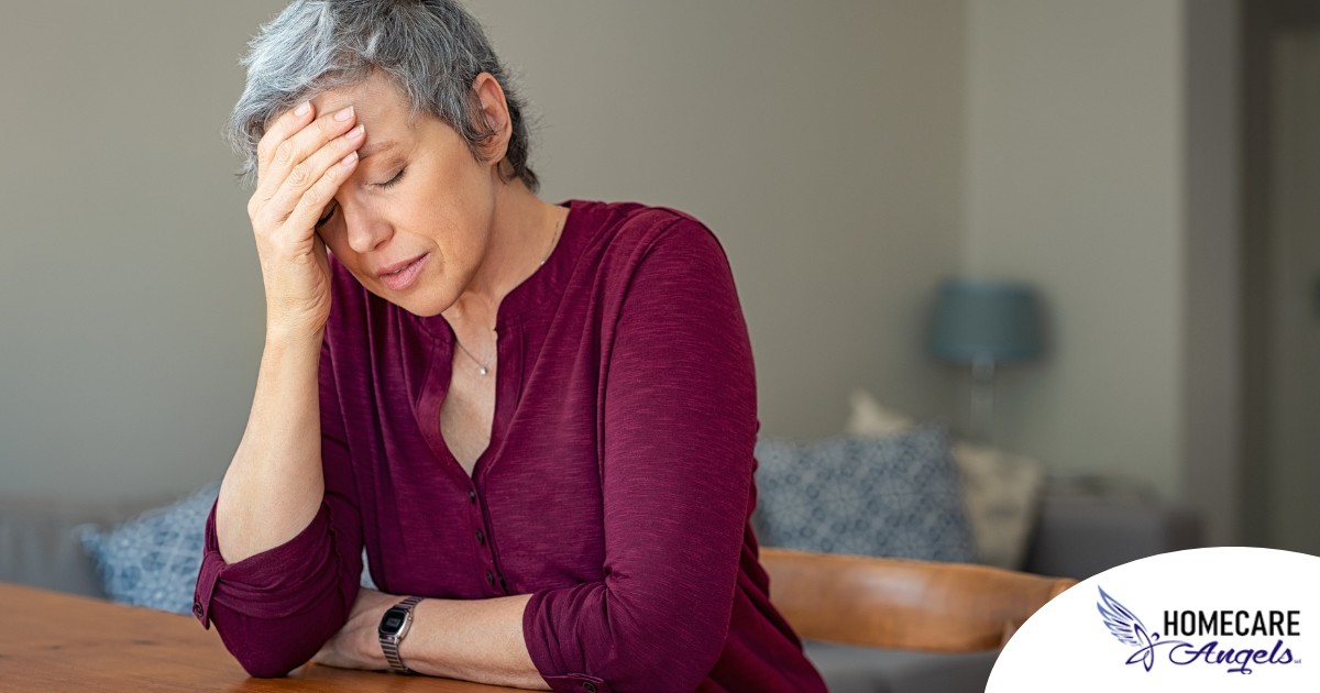 A woman holds her head in her hand, representing the stress that new family caregivers go through.