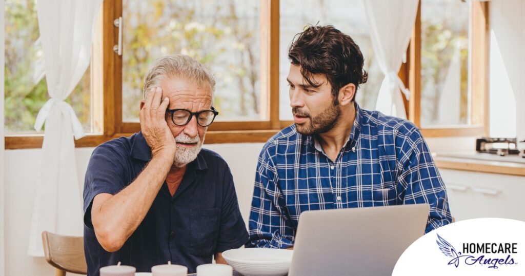 A man looks at a computer with his father who is confused, representing one of the early signs of dementia.